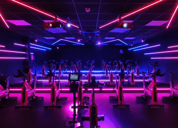 A high-tech spinning studio lit in purple and blue