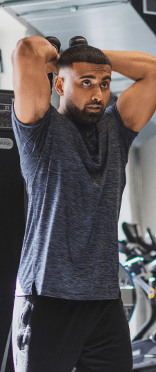 A man lifts small dumbbells over and behind his head.